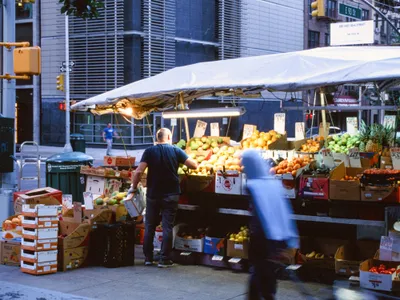A corner fruit stand under a white awning
